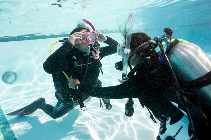 Instructeur en cursist oefenen onderwatervaardigheden in het zwembad